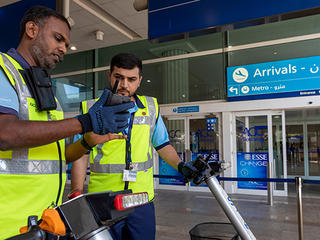 dubai airport trolley staff with tactilon dabat device outside the arrivals