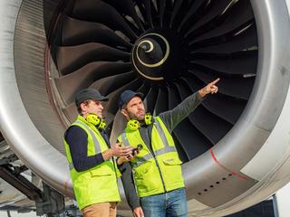 Ground handlers discussing in front of a airplane jet engine