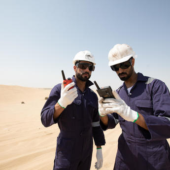 tactilon agnet and tetra - 2 business critical workers looking at their devices in the dessert