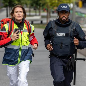 paramedic female and police male running for an emergency with their phones in hands