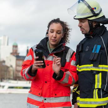 two_public_safety_firefighters_woman_holding_a_device.jpg