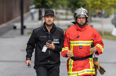 security and fireman running in the street phone in their hand security and fireman running in the street phone in their hand