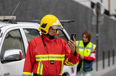 push to talk fireman using a smartphone white car and a medic in the background push to talk - fireman using a smartphone white car and a medic in the background
