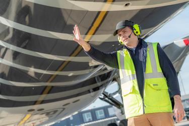 aircraft turnaround maintenance man on the tarmac raising his hand under a plane.jpg