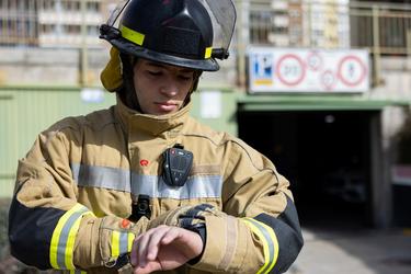 Fireman equiped with PPT accessory and body cam looking at his smart watch Fireman equiped with PPT accessory and body cam looking at his smart watch
