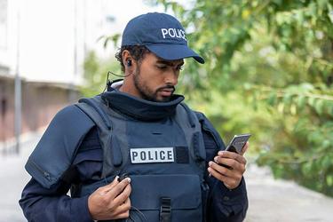 Police officer looks at his smartphone Police officer looks at his smartphone