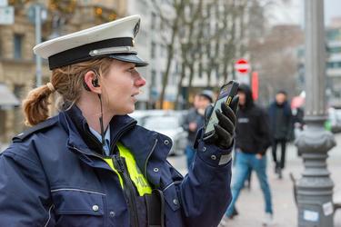 Police woman using Agnet group call feature on a ruggedized smartphone in the street Police woman using Agnet group call feature on a ruggedized smartphone in the street