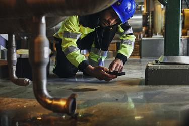 Industry worker checking a leaking pipe and inofrming about that with Agnet
