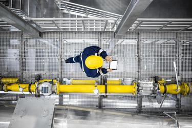 Industry worker holding a device in a manufacturing facility Industry worker holding a device in a manufacturing facility