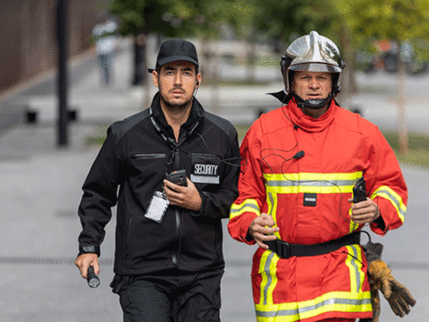 security and fireman running in the street phone in their hand