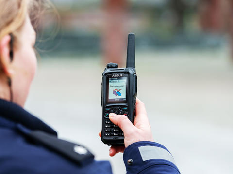 Police officer scrolling the menu of a TH9 TETRA terminal