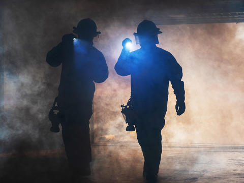 Firemen wandering in the smoke with lights