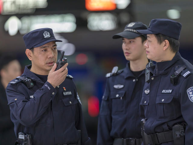 TETRA - Guangzhou police speaking to a device with other two standing next to him