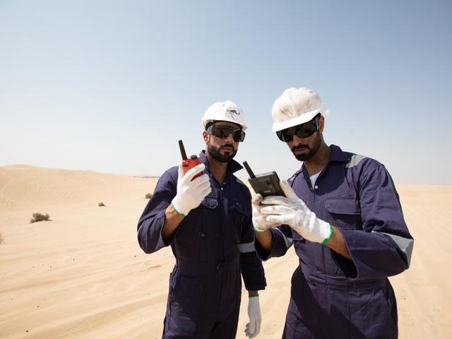 tactilon agnet and tetra - 2 business critical workers looking at their devices in the dessert