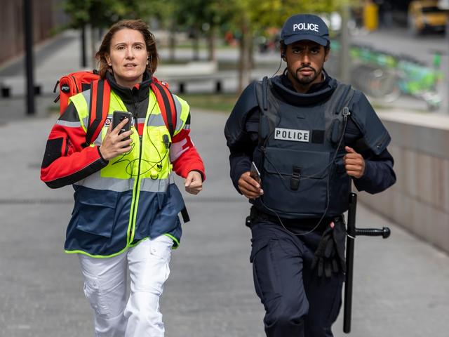paramedic female and police male running for an emergency with their phones in hands
