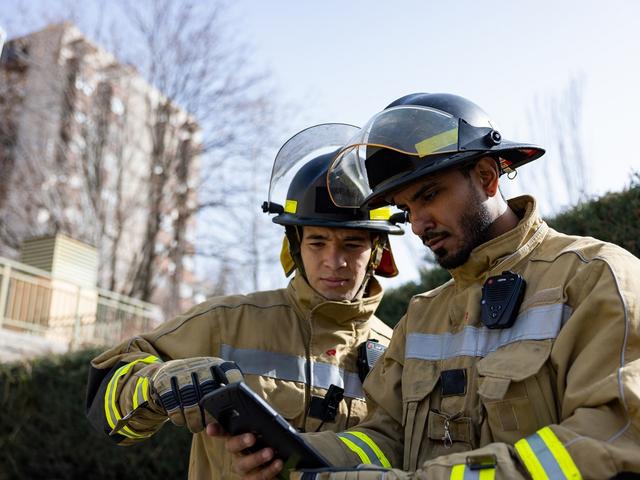 two firemen looking at a ruggedized tablet one showing something on the screen