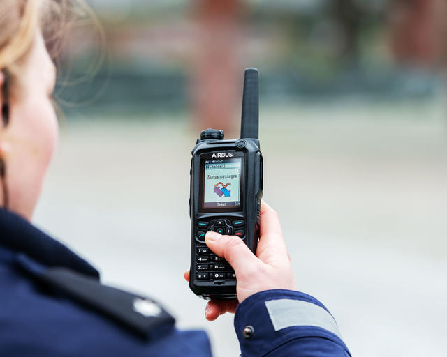 Police officer scrolling the menu of a TH9 TETRA terminal
