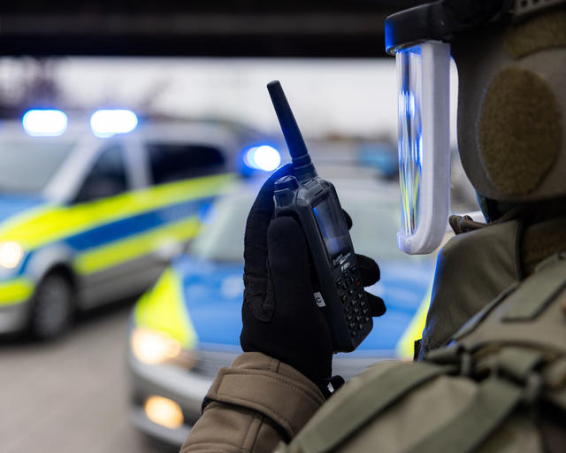 Swat officer talking to a TPH900 Tetrapol terminal with police cars on the background Swat officer talking to a TPH900 Tetrapol terminal with police cars on the background