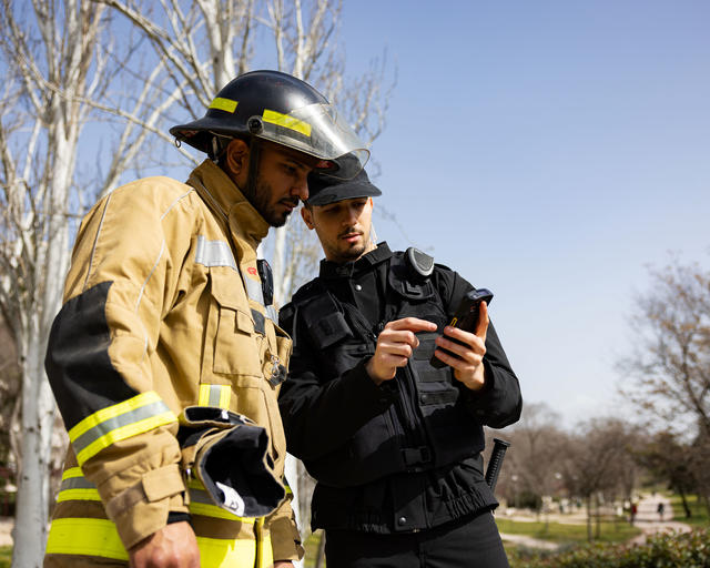 Fireman and security officer discussing a mission usign Agnet and a Zebra smartphone Fireman and security officer discussing a mission usign Agnet and a Zebra smartphone