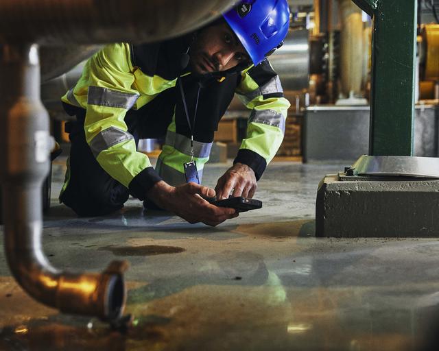 Industry worker checking a leaking pipe and inofrming about that with Agnet Industry worker checking a leaking pipe and inofrming about that with Agnet