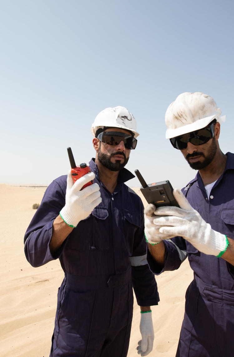 tactilon agnet and tetra - 2 business critical workers looking at their devices in the dessert