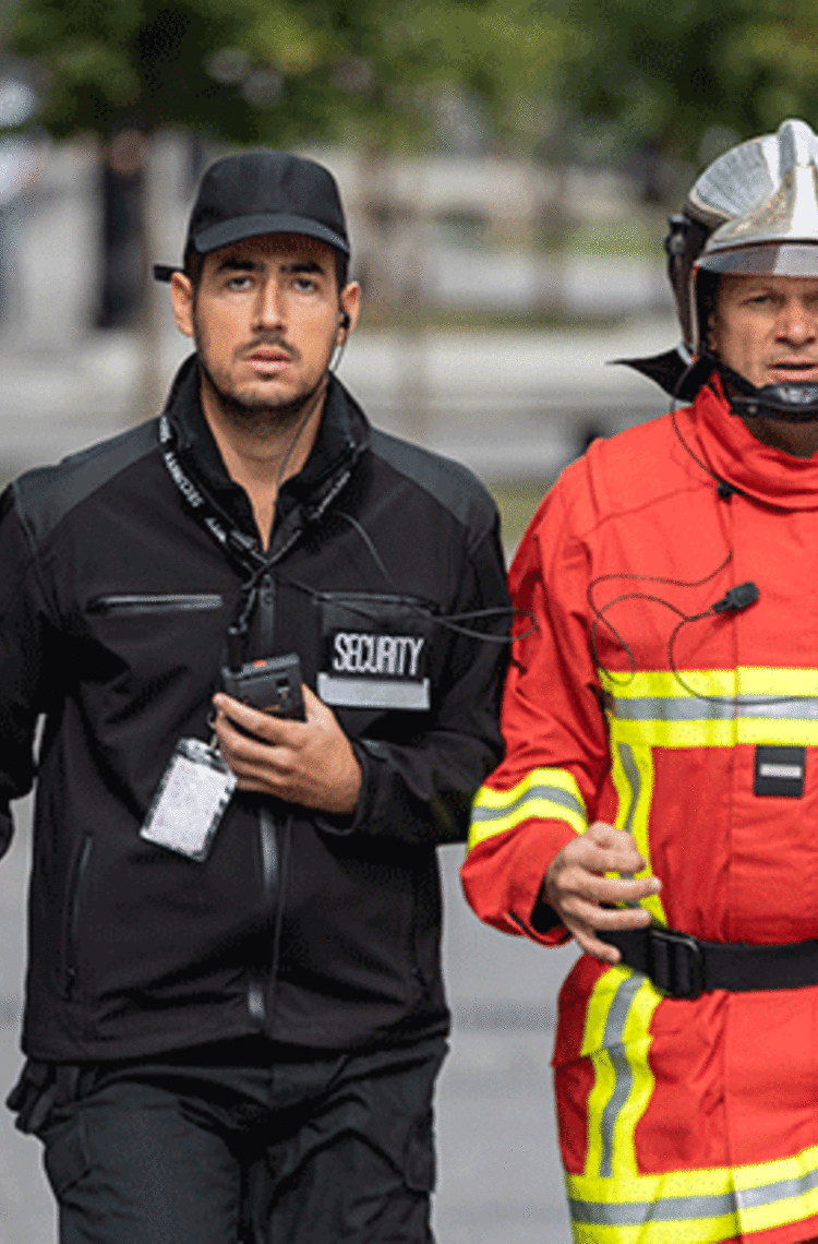 security and fireman running in the street phone in their hand