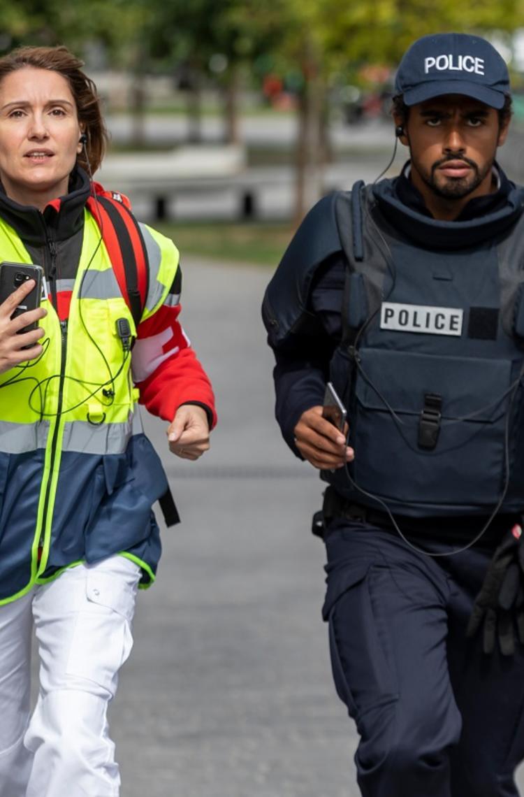 paramedic female and police male running for an emergency with their phones in hands