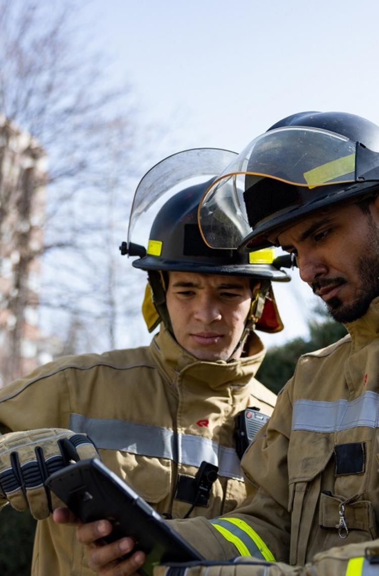 two firemen looking at a ruggedized tablet one showing something on the screen two firemen looking at a ruggedized tablet one showing something on the screen