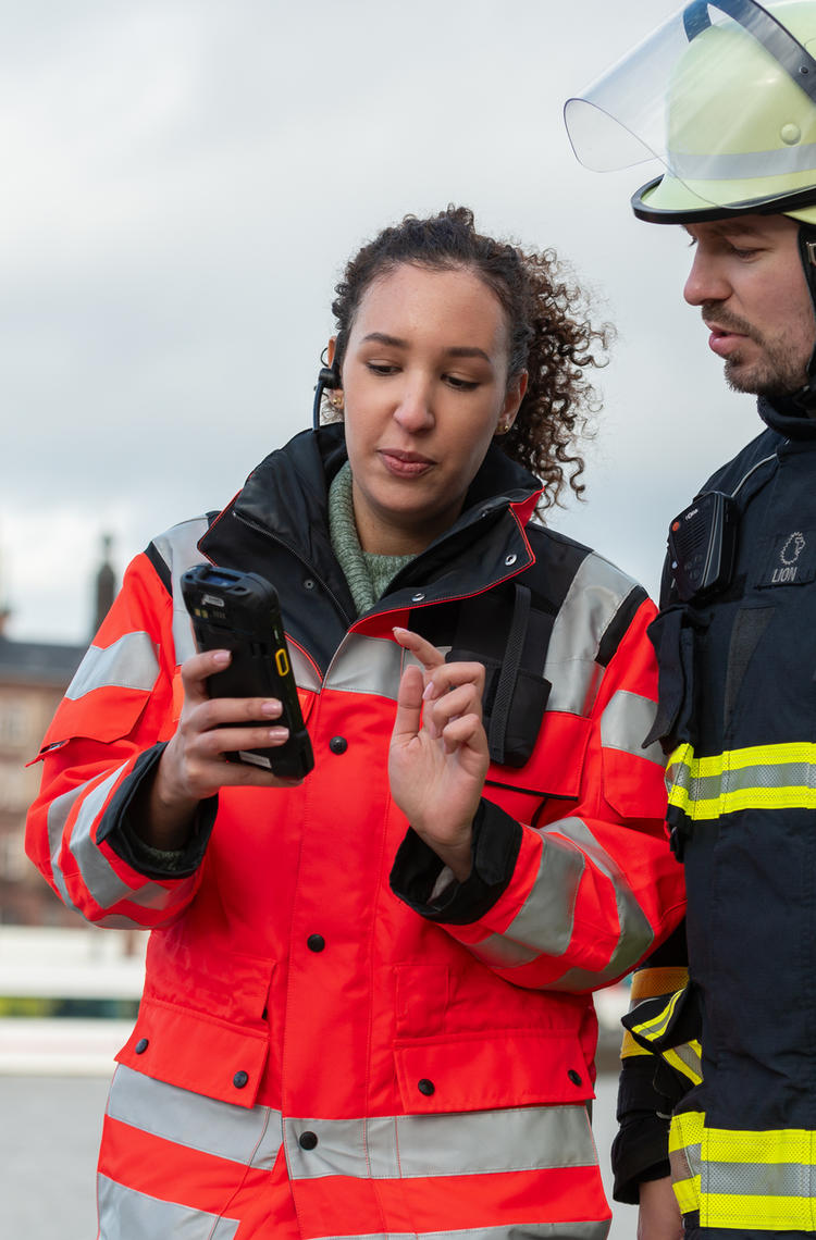 two_public_safety_firefighters_woman_holding_a_device.jpg two_public_safety_firefighters_woman_holding_a_device.jpg