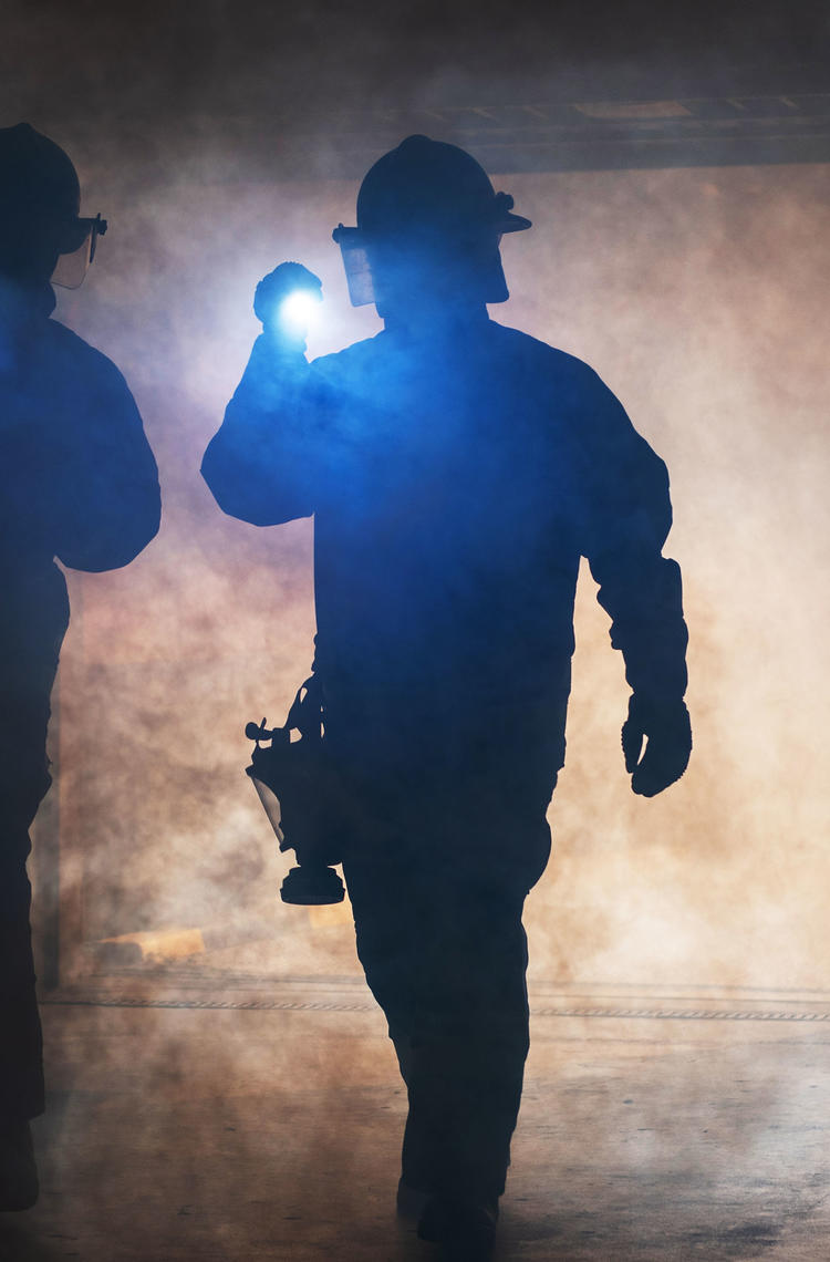 Firemen wandering in the smoke with lights