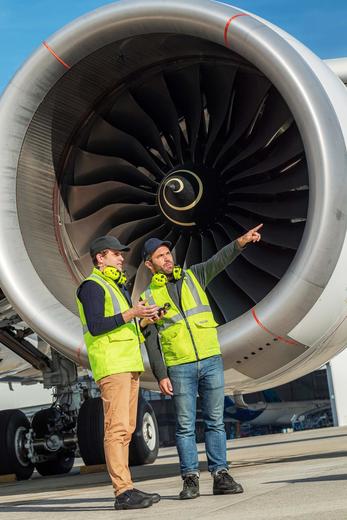 Ground handlers discussing in front of a airplane jet engine